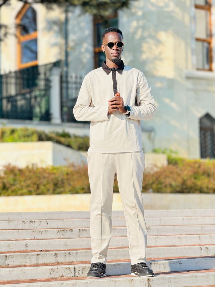 who-we-are Young man in sunglasses posing confidently outdoors in Istanbul, with a historical backdrop.