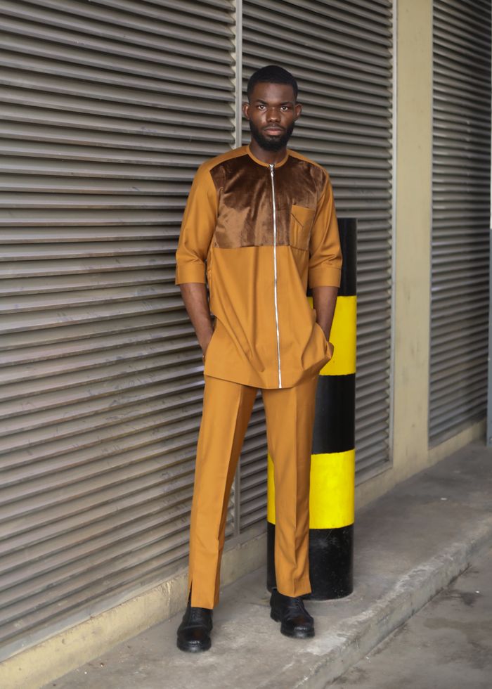 services-03 Stylish man in a brown outfit poses confidently outdoors against industrial backdrop.